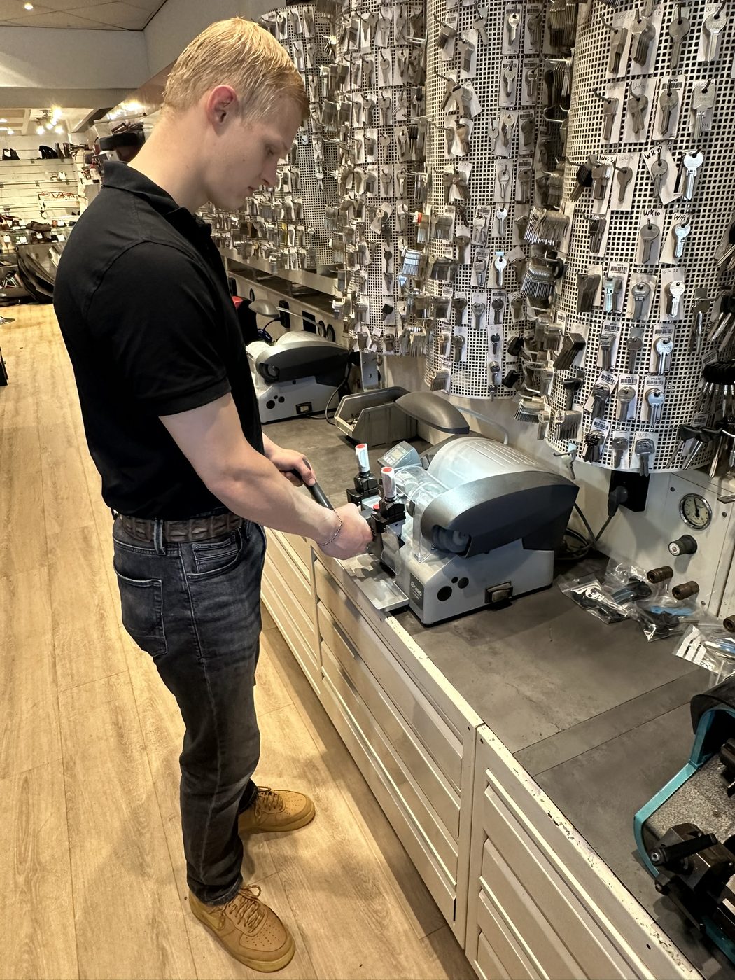 Sleutelspecialist freest een autosleutel op de sleutelmachine in de winkel in Enschede