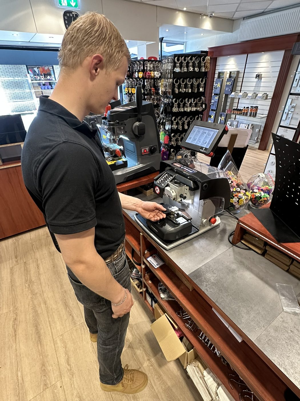 Sleutelspecialist aan de balie met sleutelmachines in de winkel van Westendorp in Winkelcentrum Enschede Zuid